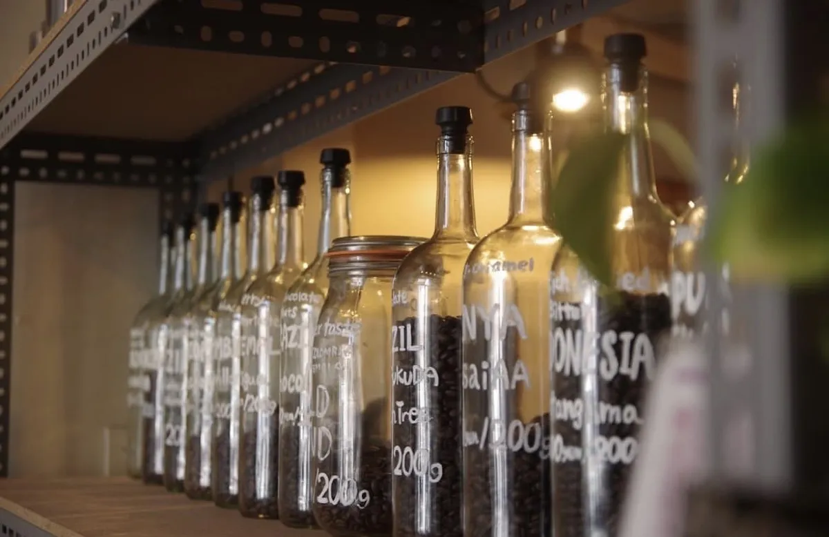 産地別のコーヒー豆が瓶に並ぶ棚